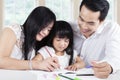 Friendly parents help their kid wrote on the book Royalty Free Stock Photo