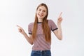 Friendly, pleasant cheerful woman in striped t-shirt with long fair hair, raise hands pointing sideways, show left and