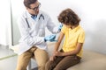 Pediatrician giving shot to boy in clinic stock photo
