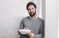 Friendly psychologist standing with clipboard, leaning at wall Royalty Free Stock Photo