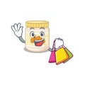 A friendly rich almond butter waving and holding Shopping bag