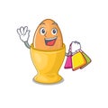 A friendly rich egg cup waving and holding Shopping bag