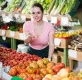 Friendly salesgirl proposing fresh fruits and vegetables in supermarket Royalty Free Stock Photo