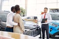 Friendly salesman and beautiful couple in car showroom