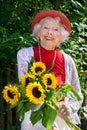 Friendly senior lady with a bunch of sunflowers.