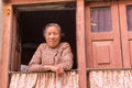 Friendly senior Nepalese woman in the window of her house in Kirtipur