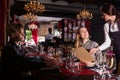 Friendly smiling female waiter bringing order to visitors in luxurious restaurant Royalty Free Stock Photo