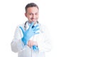 Friendly smiling medic or doctor pulling blue latex gloves