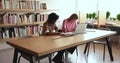 Friendly smiling multiethnic schoolmates studying in library