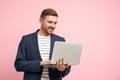 Smiling relaxed middle-aged man in office look holding laptop computer isolated on pink background Royalty Free Stock Photo