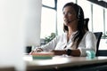 Friendly smiling woman call center operator with headset using computer at office. Royalty Free Stock Photo