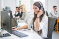 Friendly smiling woman call center operator with headset using computer at office. Royalty Free Stock Photo