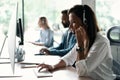 Friendly smiling woman call center operator with headset using computer at office. Royalty Free Stock Photo