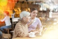 Young girl helping elderly lady to use laptop in cafe Royalty Free Stock Photo