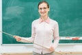Friendly teacher standing in front of blackboard in class