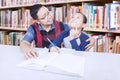 Friendly teacher teaching student in library