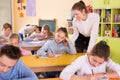 Teacher woman helping children during lesson in schoolroom