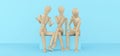 Friendly team. Communication, discussion, the concept of unity. Three wooden mannequins sit in various poses and talk animatedly. Royalty Free Stock Photo
