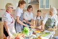 Friendly three generations of women preparing cooking pizza, standing in kitchen Royalty Free Stock Photo