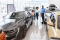 Friendly vehicle dealer offering black family selection of new cars at auto showroom Royalty Free Stock Photo