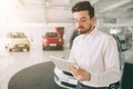 Friendly vehicle salesman presenting new cars at showroom. Photo of young male consultant showing new car in auto show Royalty Free Stock Photo