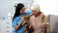 Friendly volunteer covering disabled aged woman with blanket, help nursing home Royalty Free Stock Photo