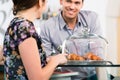 Friendly waiter offering to young female customer fresh French c