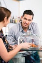 Friendly waiter offering to young female customer fresh French c