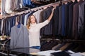 Friendly woman seller displaying diverse men suits