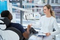 Friendly woman stomatologist shaking hand to male client before checkup