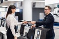 Friendly woman staff taking passport from passenger at airport check in desk