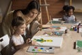 Friendly young art teacher giving artistic lesson to kids Royalty Free Stock Photo