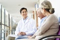 Young asian doctor talking to senior couple patients in hospital hallway Royalty Free Stock Photo