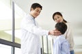 Young asian doctor talking to mother and son in hospital