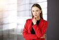 Friendly young business woman or female student dressed in red coat is standing straight and looking at camera in a Royalty Free Stock Photo