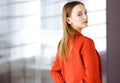 Friendly young business woman or female student dressed in red coat is standing straight and looking at camera. Urban Royalty Free Stock Photo