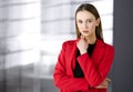 Friendly young business woman or female student dressed in red coat is standing straight and looking at camera. Urban Royalty Free Stock Photo