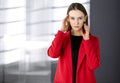Friendly young business woman or female student dressed in red coat is standing straight and looking at camera. Urban Royalty Free Stock Photo