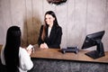 Friendly young concierge standing behind a reception counter giving room information to guest checking into a hotel Royalty Free Stock Photo