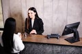 Friendly young concierge standing behind a reception counter giving room information to guest checking into a hotel Royalty Free Stock Photo