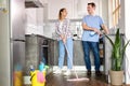 Friendly Young Couple Cleaning Home, In Kitchen. Woman Wiping Floor With Mop, Husband Helping Royalty Free Stock Photo