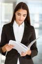 A friendly young dark hair businesswoman or female student dressed in a black suit is standing and looking through some