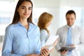 A friendly young dark hair businesswoman or female student is standing with some papers in the office