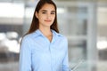 A friendly young dark hair businesswoman or female student is standing with some papers in the office