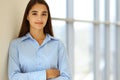 A friendly young dark hair businesswoman or female student is standing with some papers in the office