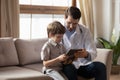 Friendly young pediatrician showing cartoons on tablet to little patient.