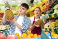 Friendly young saleswoman helps a guy buyer choose a pineapple