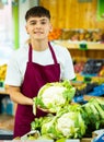 Portrait of joyful male merchandiser with cauliflower in hands at grocery supermarket