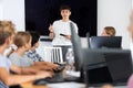 Friendly young teacher standing near an interactive whiteboard telling new material to teenage students in school Royalty Free Stock Photo