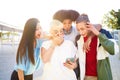 Friends amazed watching the smart phone outdoor. Young smiling people sharing with mobile cell outdoors. Royalty Free Stock Photo